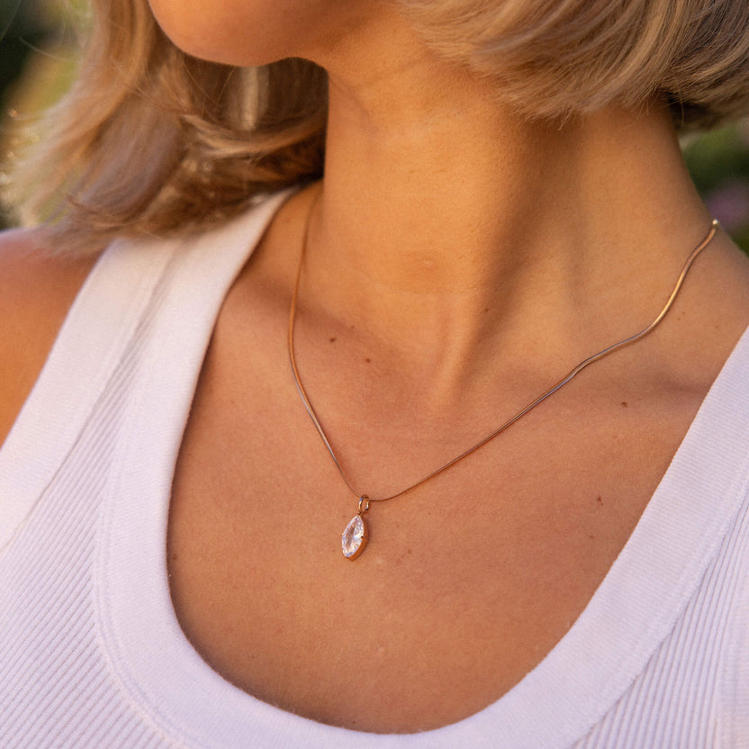 Goldene Kette mit marquiseförmigem Anhänger, getragen in warmem Licht – PURELEI.