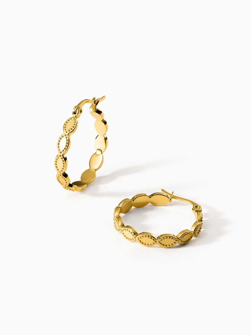 Goldene Creolen mit geschwungenem Design von PURELEI, elegant und feminin.