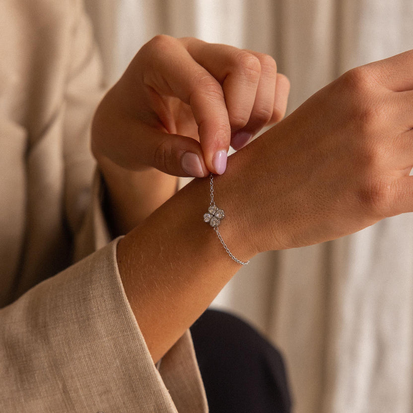 Silbernes Armband mit blütenförmigem Anhänger, getragen am Handgelenk, von PURELEI.