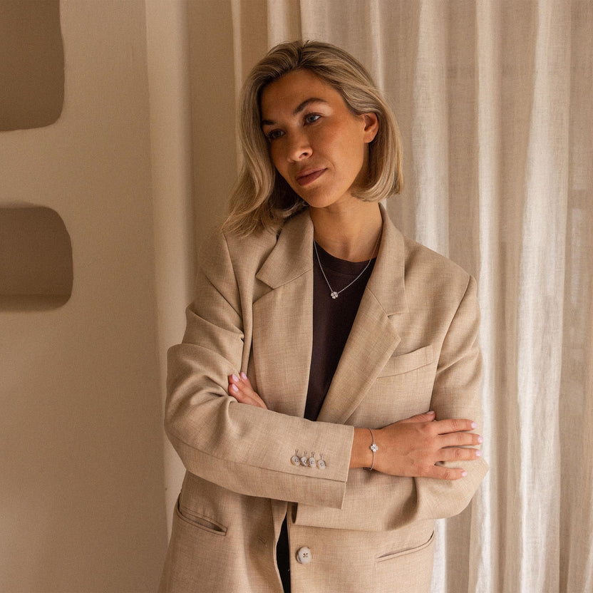 Elegante PURELEI Kette mit zartem Anhänger, getragen in einem warmen, minimalistischen Raum.