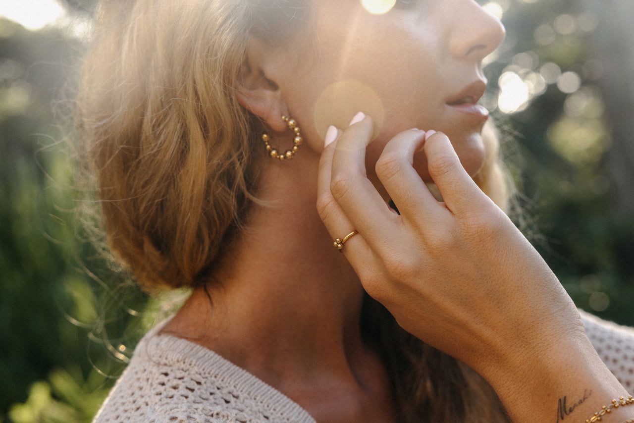 Roségoldene Creolen und Ring, PURELEI, in warmem Licht, elegant und feminin.