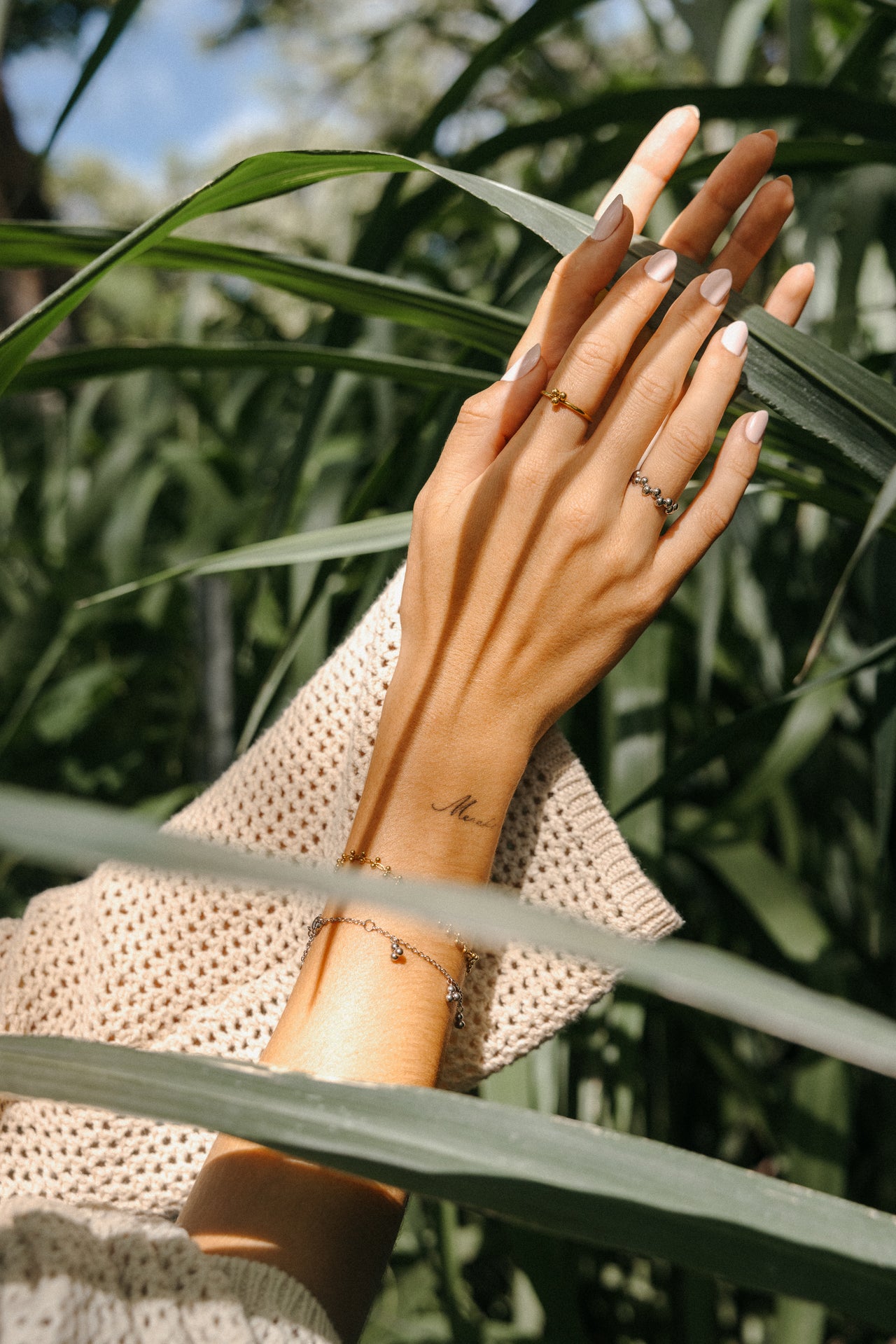 Zarte Ringe und Armbänder von PURELEI, getragen in grüner Umgebung, elegant und feminin.
