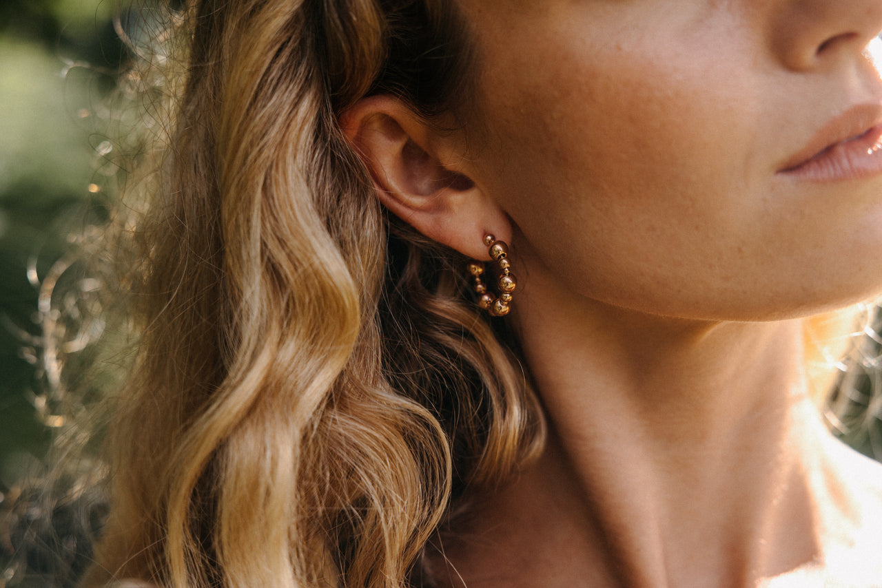 Roségoldene Creolen mit Kugeldesign, getragen von einer Frau im natürlichen Licht – PURELEI.