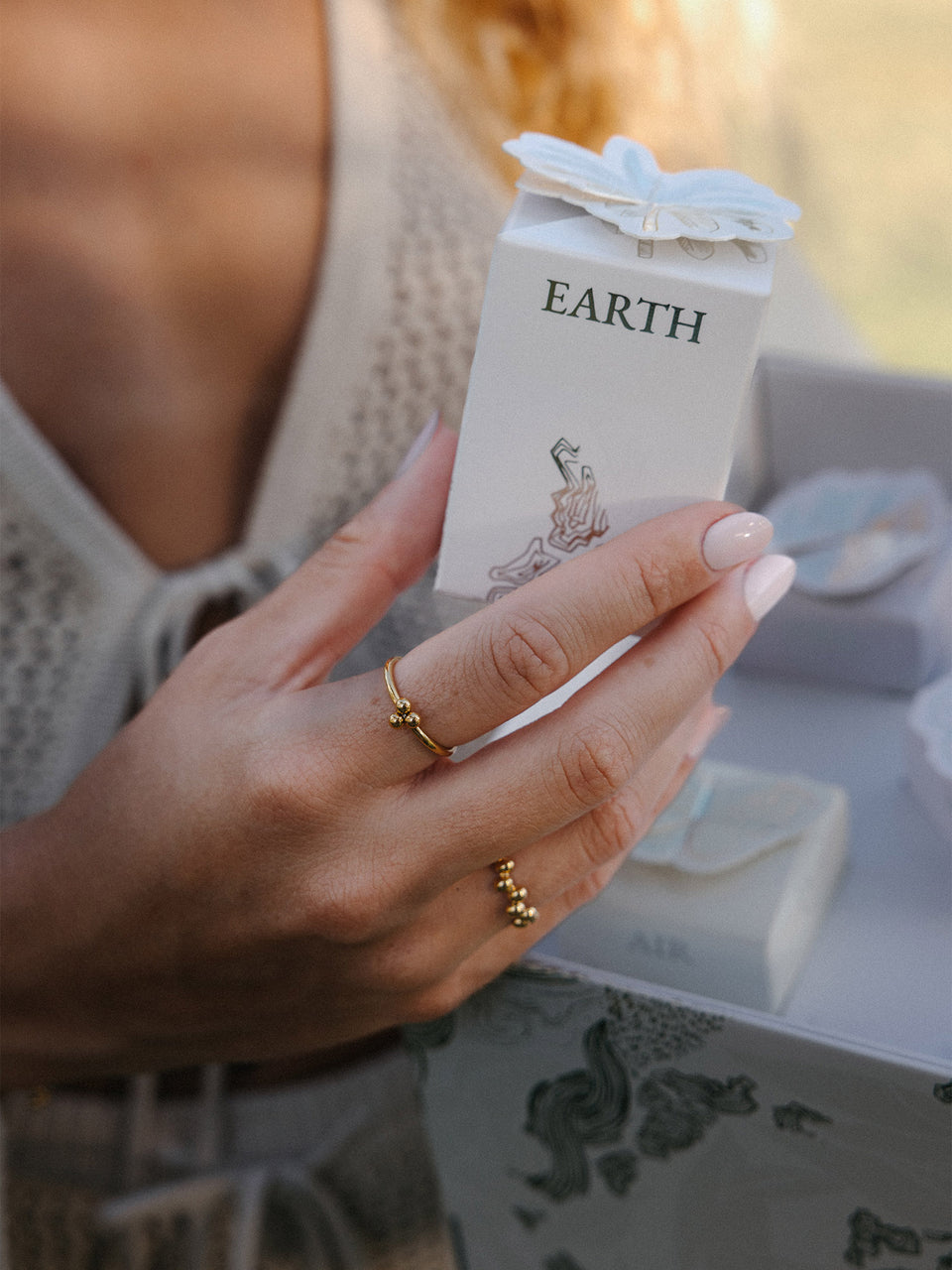Zarte, roségoldene Ringe mit Kugeldetails, gehalten in der Hand, PURELEI.