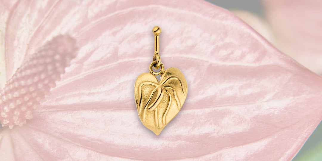Goldener Herz-Anhänger von PURELEI auf zartem Blütenblatt, elegant und feminin.