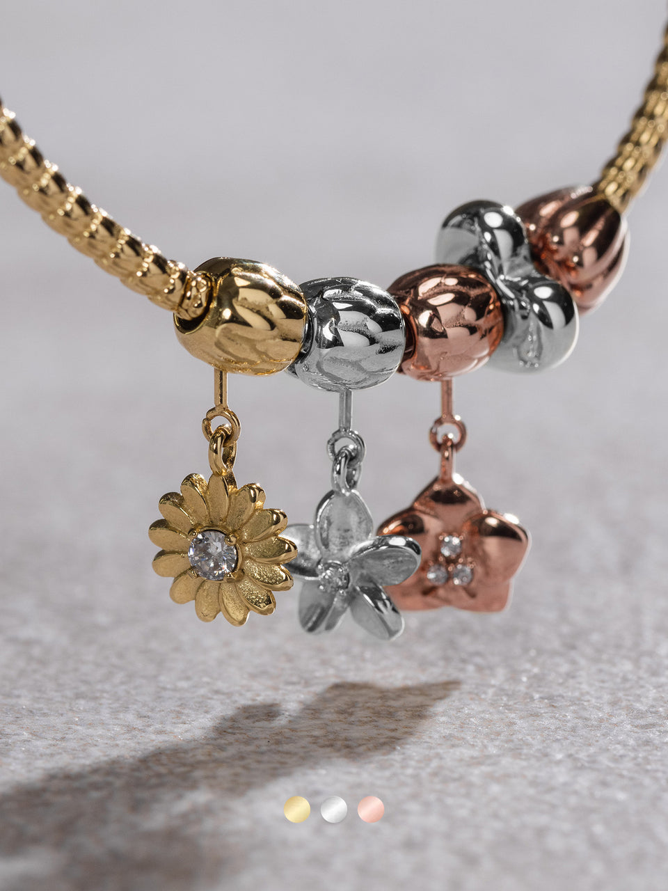 Goldene und silberne Blütenanhänger an einer Kette von PURELEI, elegant und verspielt.