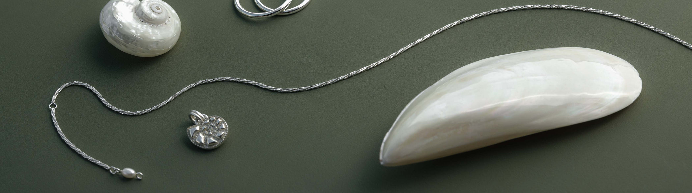 Silberne Kette mit Muschel-Anhänger und glänzenden Details von PURELEI, elegant und maritim.