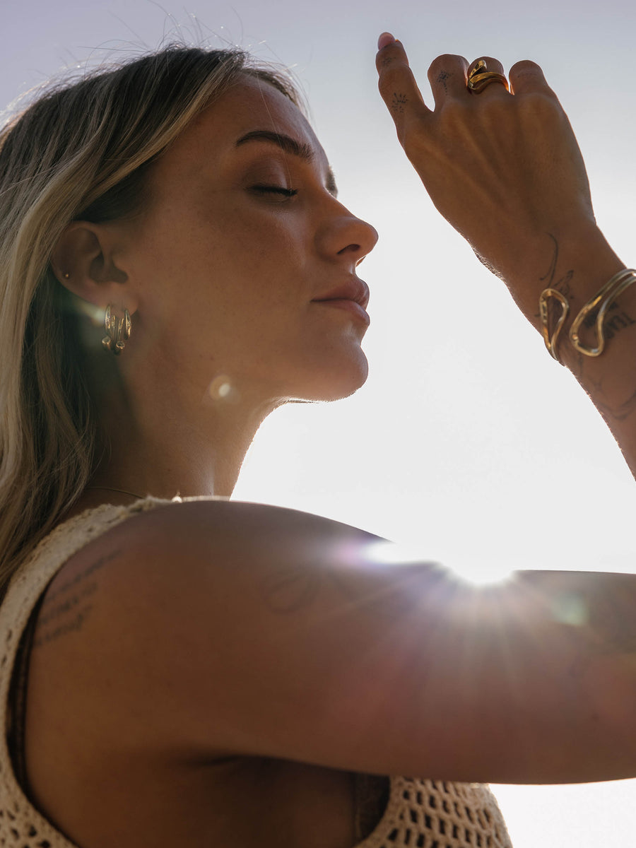 Feminine PURELEI Schmuckstücke in Roségold, getragen mit natürlicher Eleganz im Sonnenlicht.