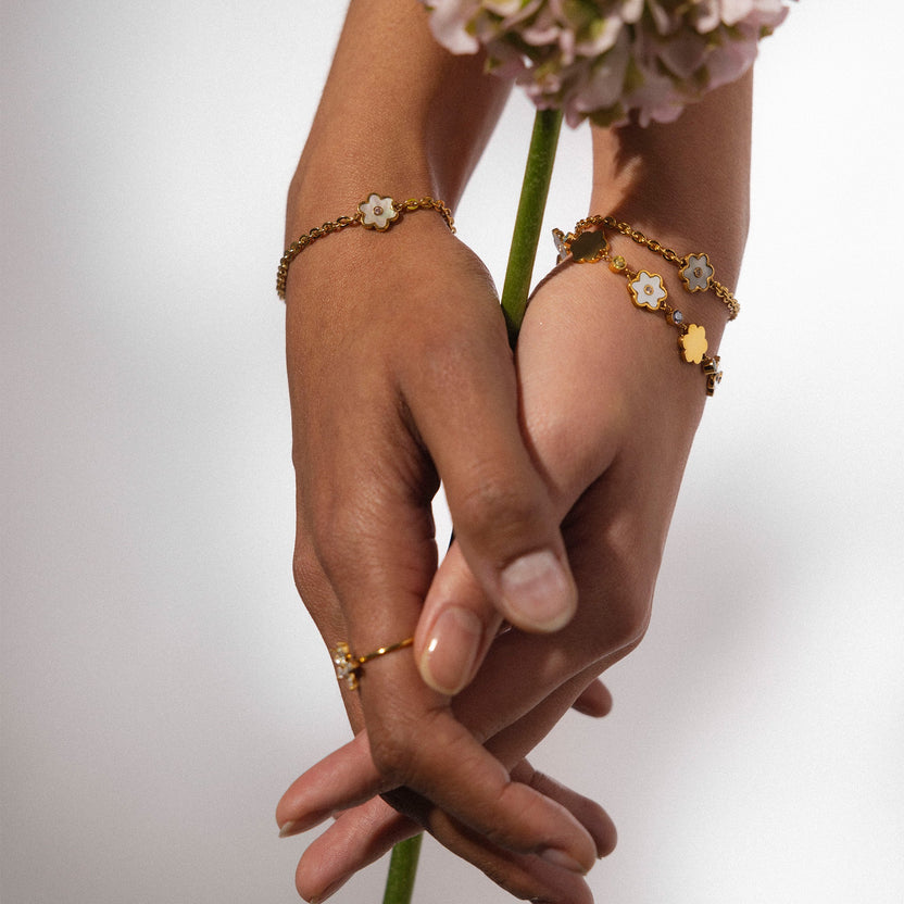 Zarte roségoldene Armbänder mit blütenförmigen Anhängern von PURELEI, elegant und feminin.