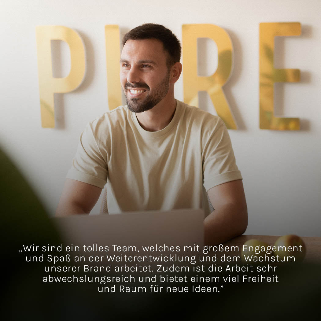 Mann in hellem Shirt lächelt vor PURELEI-Wand, strahlt positive Energie aus.