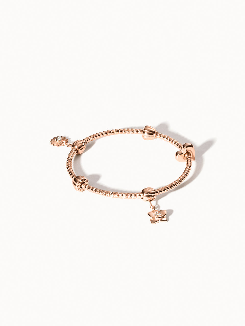 PURELEI Lei Charm Armreif Roségold mit zwei Stopper-Charms, detailreiches Blumendesign, elegant auf hellem Hintergrund