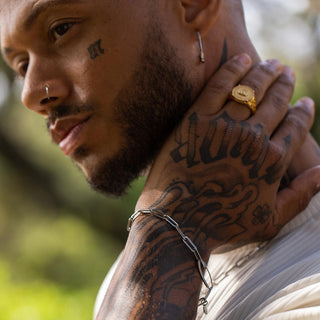 Silbernes Armband aus Kettengliedern, getragen von einem Mann mit Tattoos, PURELEI-Style.