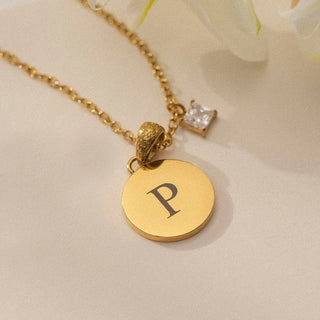 Goldene PURELEI Kette mit rundem Anhänger und P, verziert mit einem funkelnden Stein.