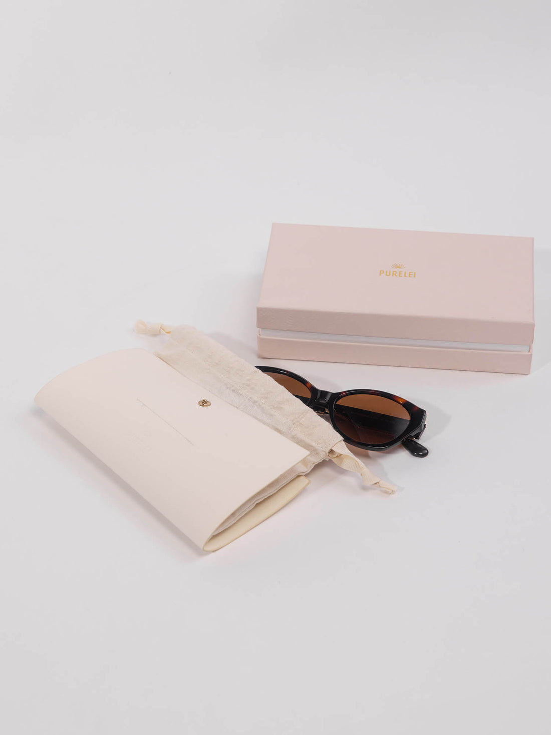 Lagoon Sonnenbrille mit dunkelbraunem Schildpatt und goldener Verzierung, elegant präsentiert mit PURELEI Etui.