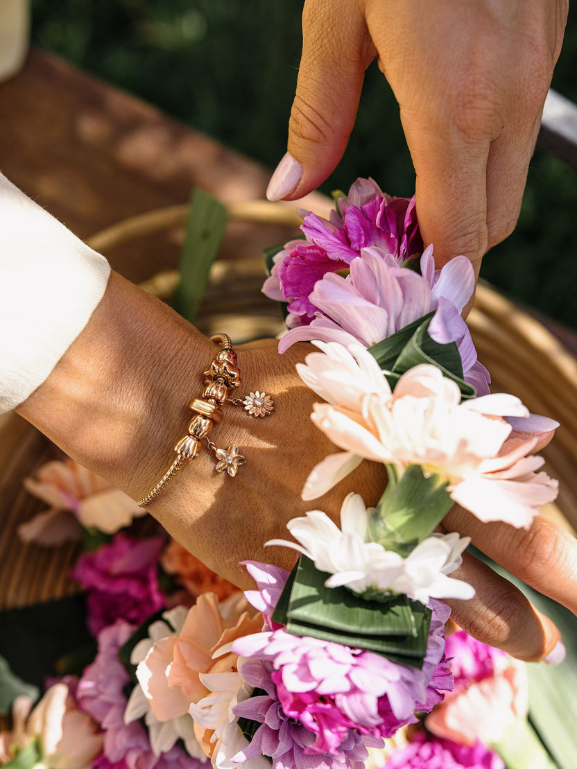 PURELEI Lei Plumeria Charm aus 18K rosévergoldetem Edelstahl mit Blüte und Zirkonia vor floralem Hintergrund