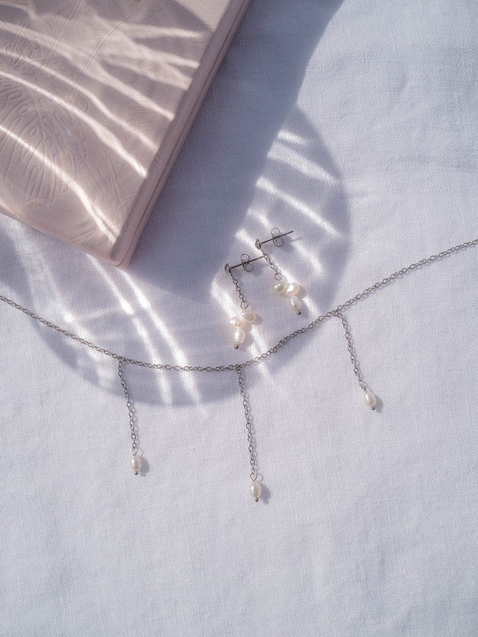 Silbernes PURELEI Mahina Club Purely Set mit natürlichen Süßwasserperlen auf weißem Leinentuch, elegant und zeitlos