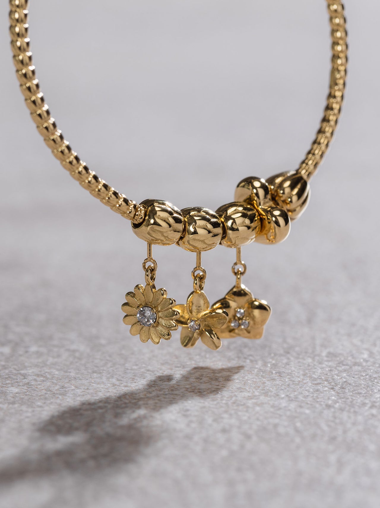 Goldene Kette mit floralen Anhängern und funkelnden Details von PURELEI.
