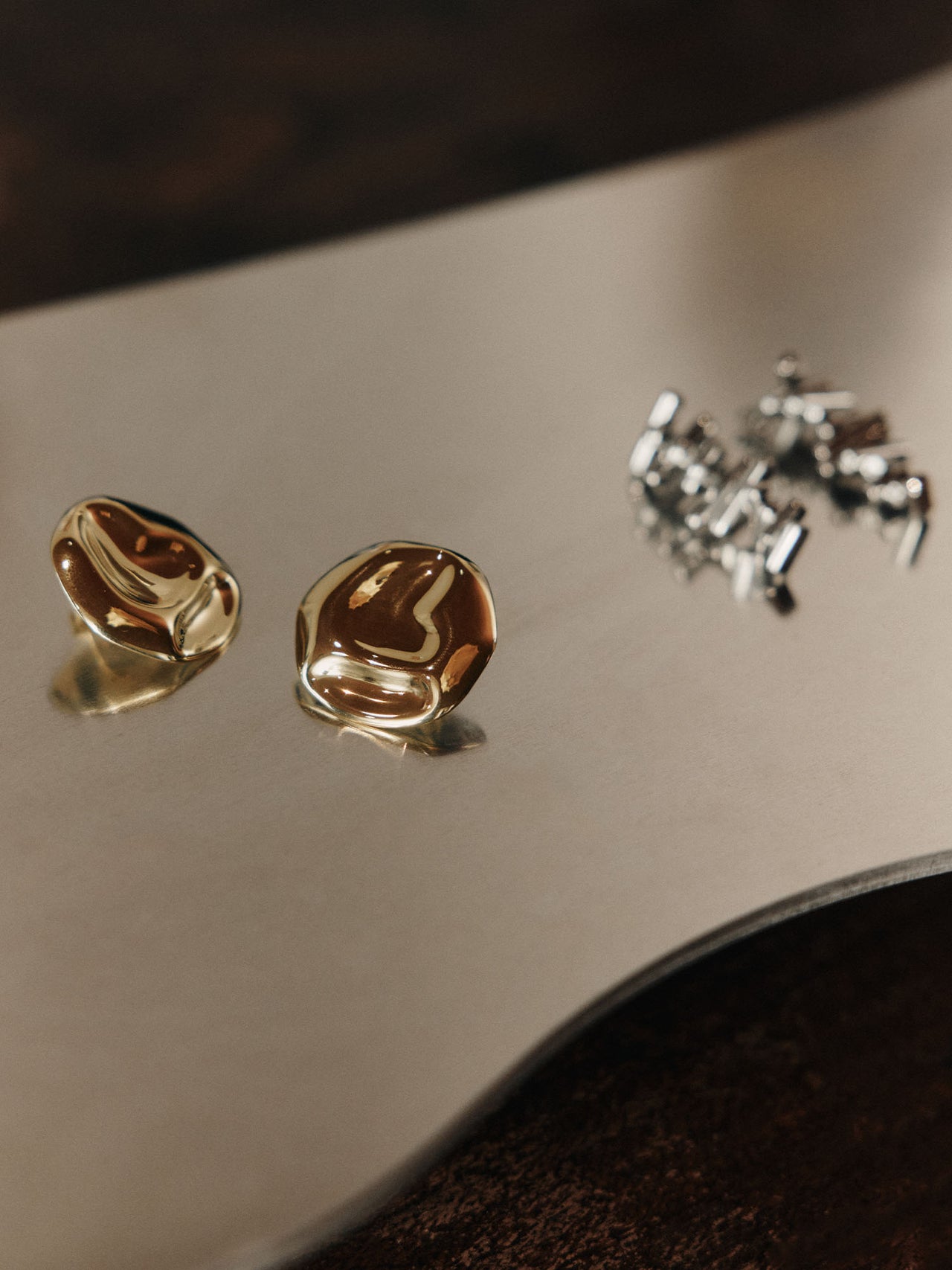 Zarte, goldene Ohrringe auf glänzendem Untergrund, PURELEI inspiriert.