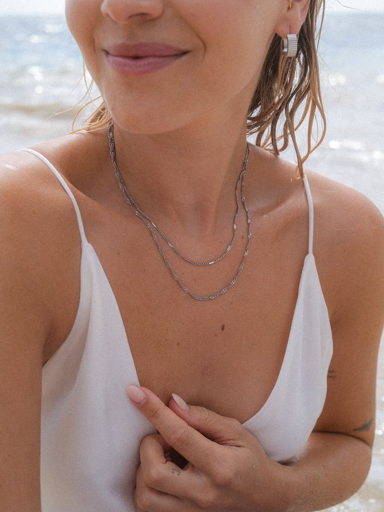 Dreifachkette aus Silber mit Wellenstruktur, getragen am Strand – PURELEI Eleganz.