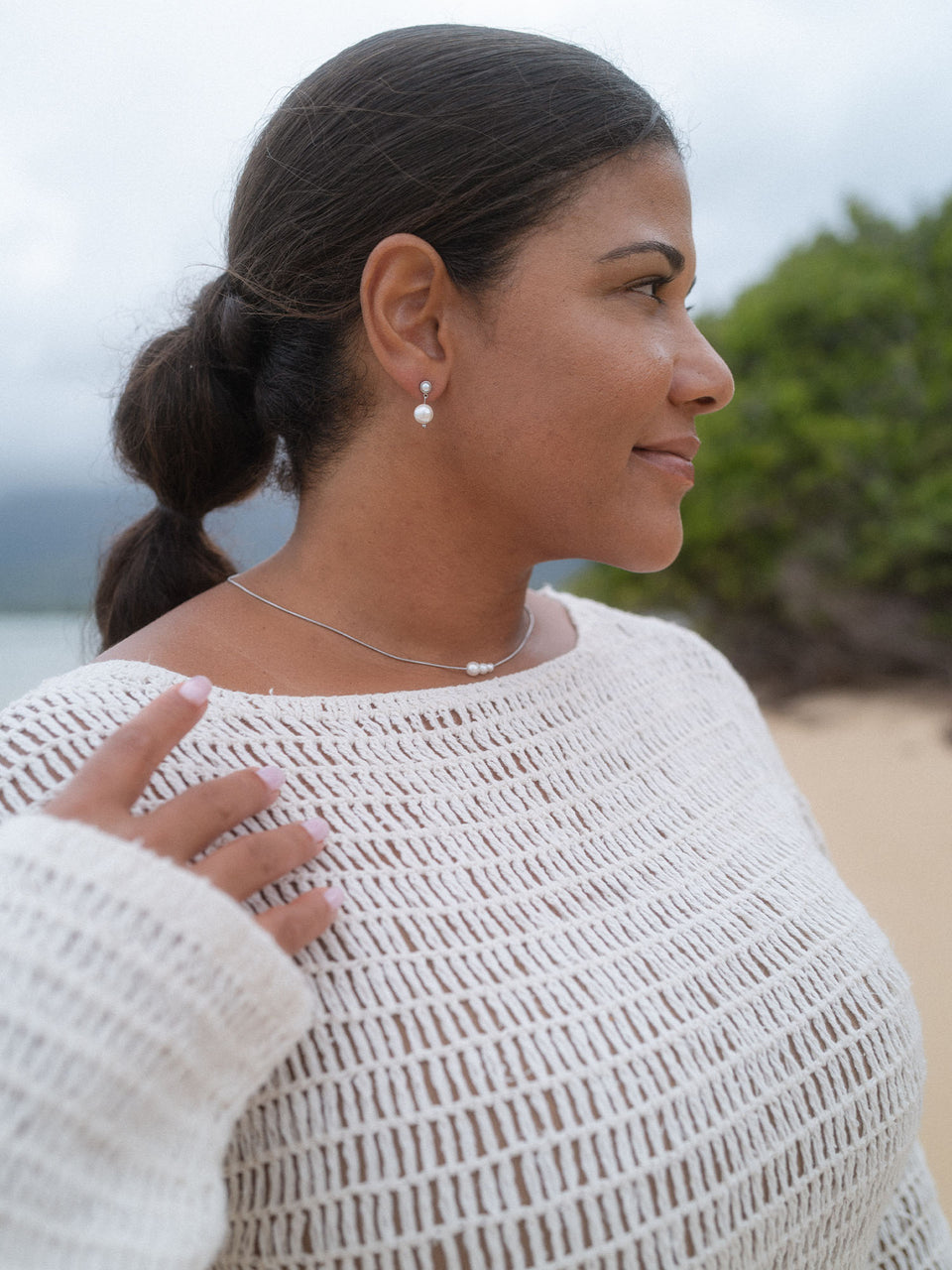 Elegante PURELEI Perlenohrringe und feine Kette, getragen am Strand in entspannter Atmosphäre.