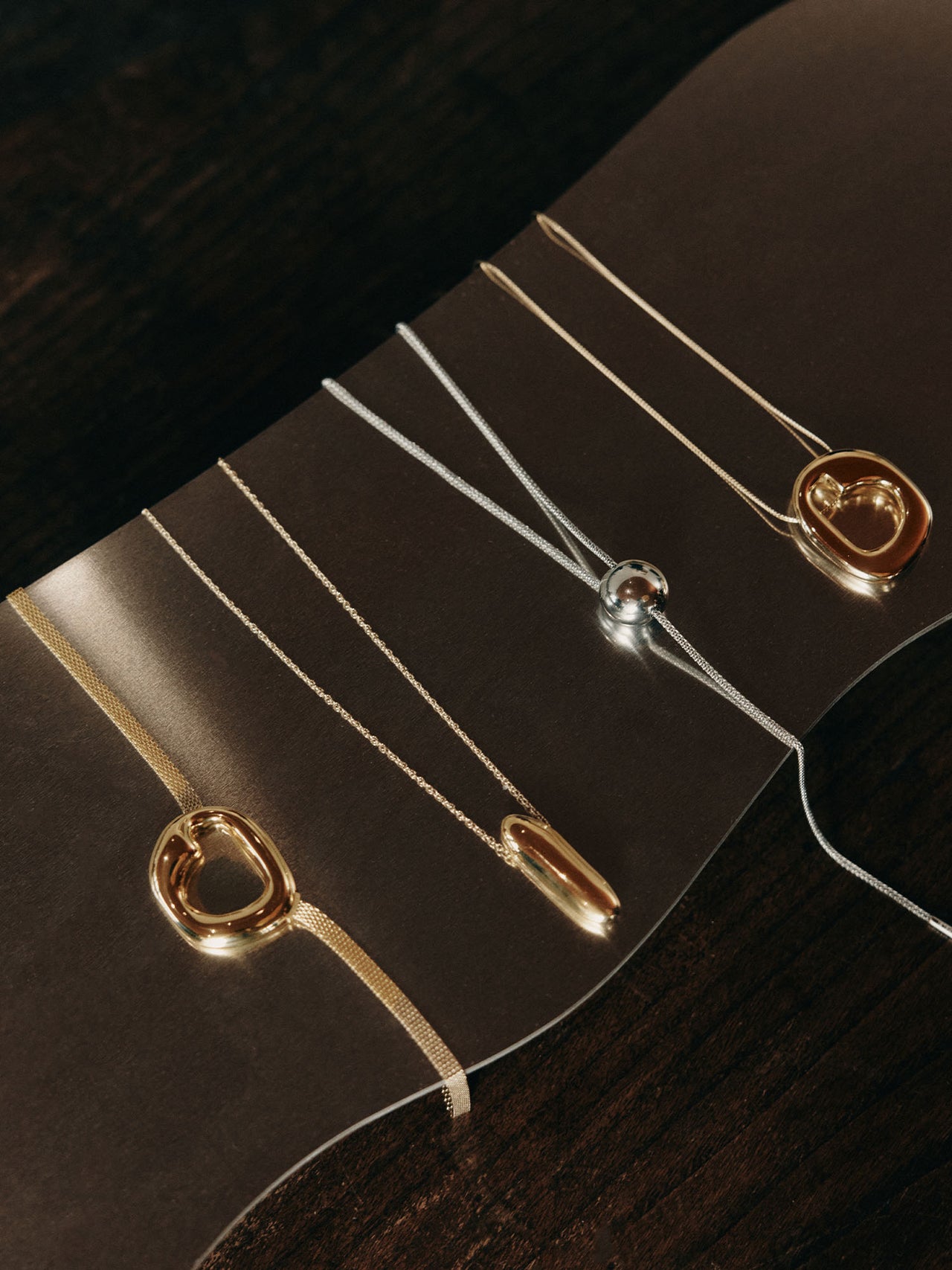 Silberne Ketten mit modernen Anhängern auf dunklem Hintergrund von PURELEI.