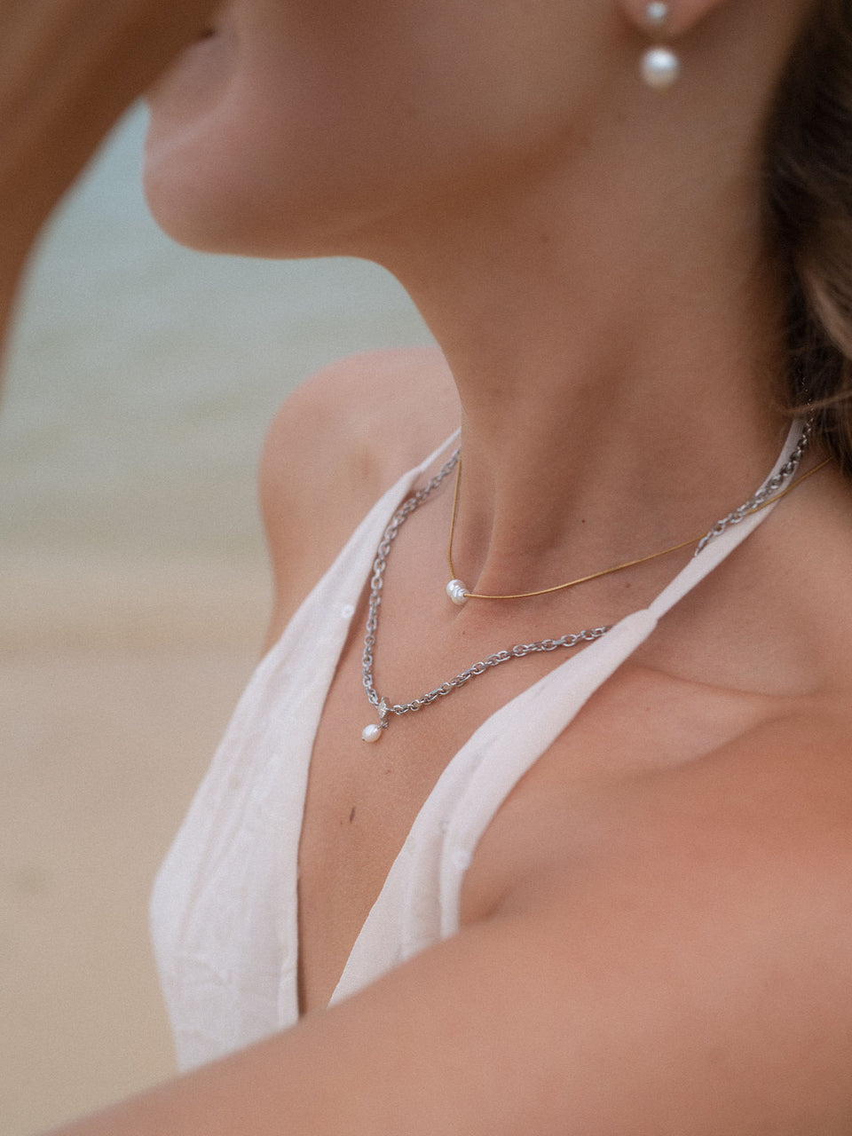 Zarte PURELEI Ketten mit Perlen, silberne Glieder und elegante Stimmung am Strand.