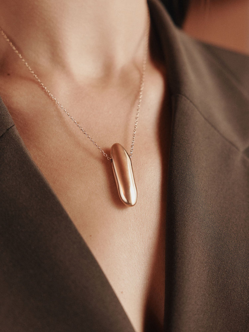 Roségoldene Kette mit elegantem Anhänger, getragen auf einem dunklen Outfit – PURELEI.