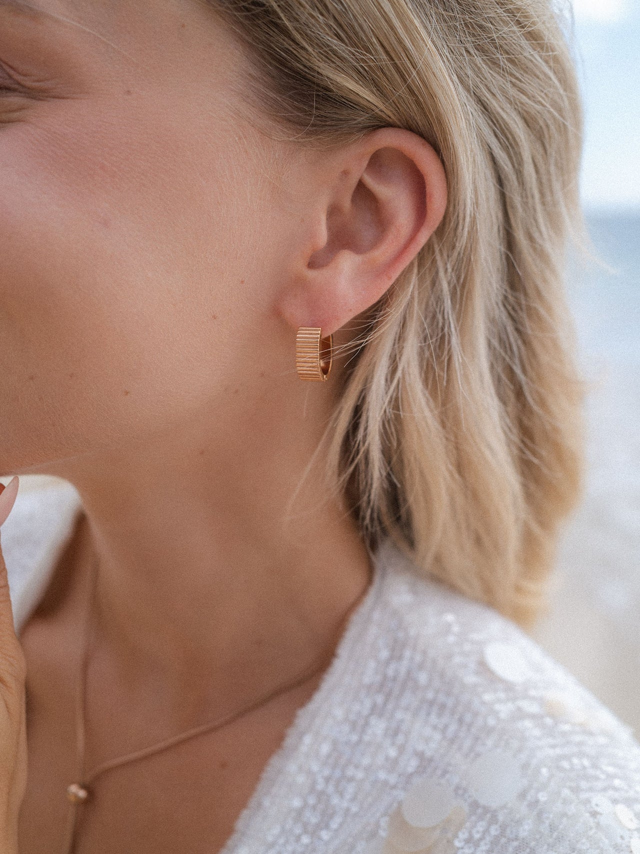 Roségoldene Creolen mit feiner Struktur, getragen von einer Frau, PURELEI inspiriert.