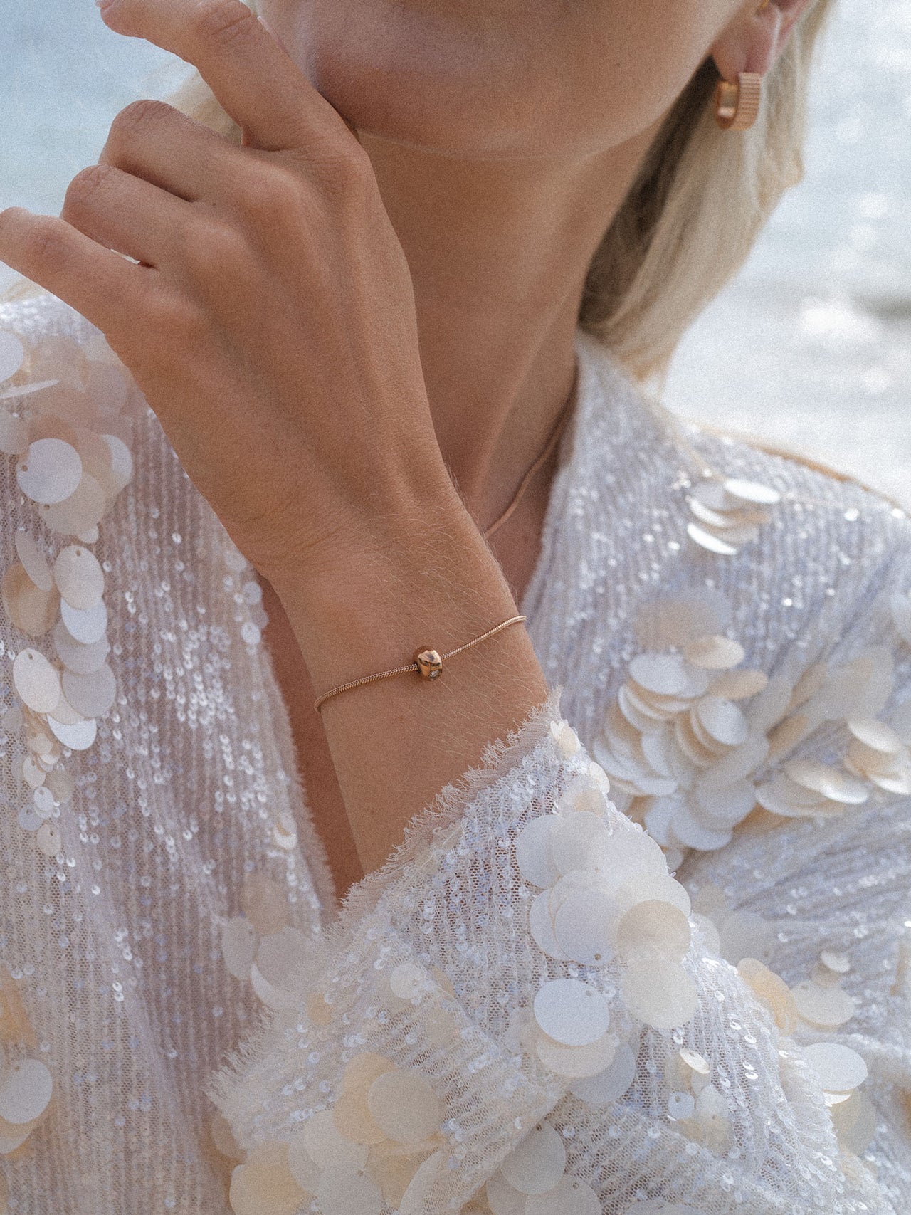 Roségoldenes Armband mit zartem Anhänger, getragen auf glitzerndem Stoff – PURELEI Eleganz.
