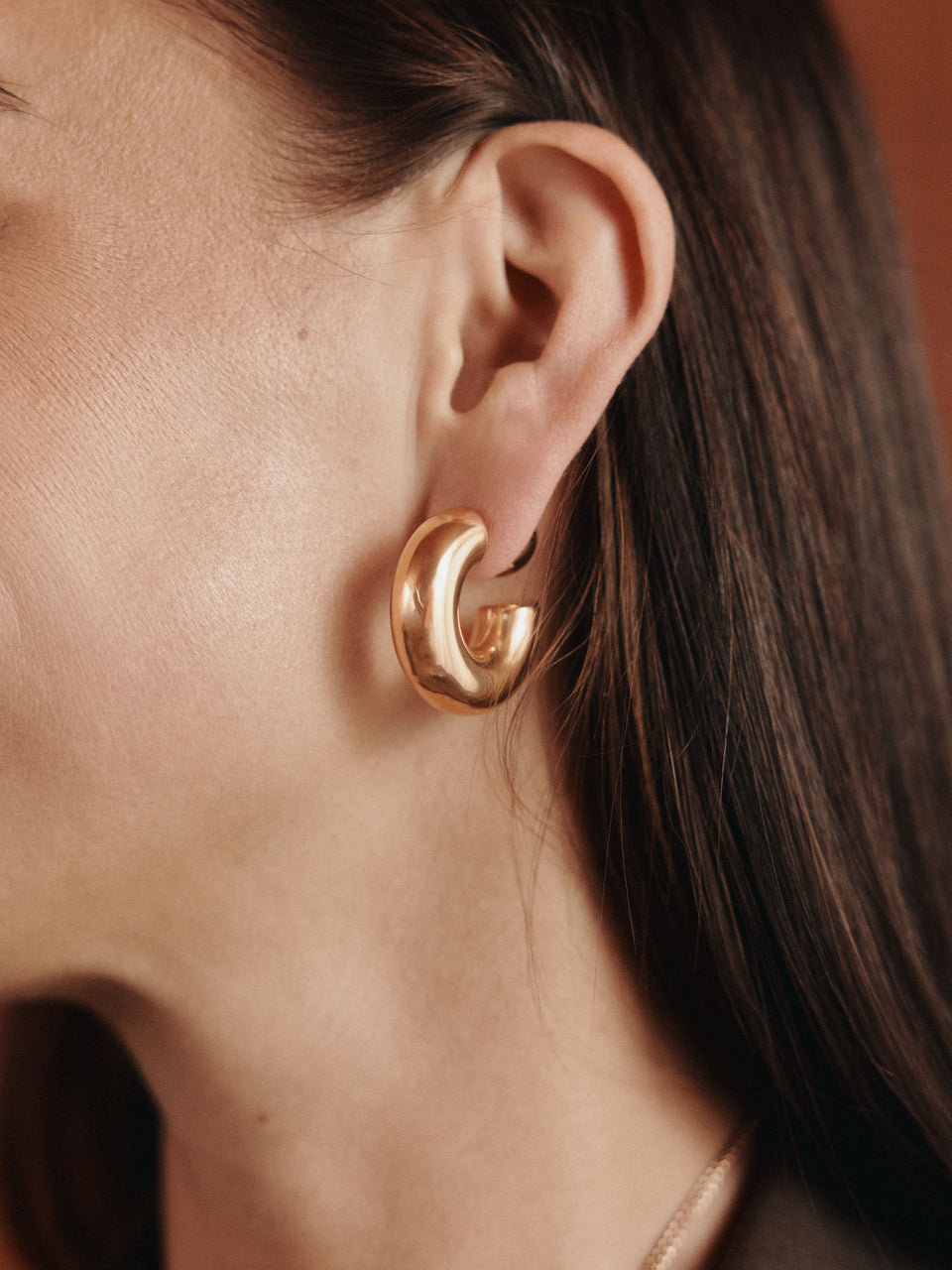 Roségoldene Creolen mit geschwungenem Design, getragen von PURELEI.