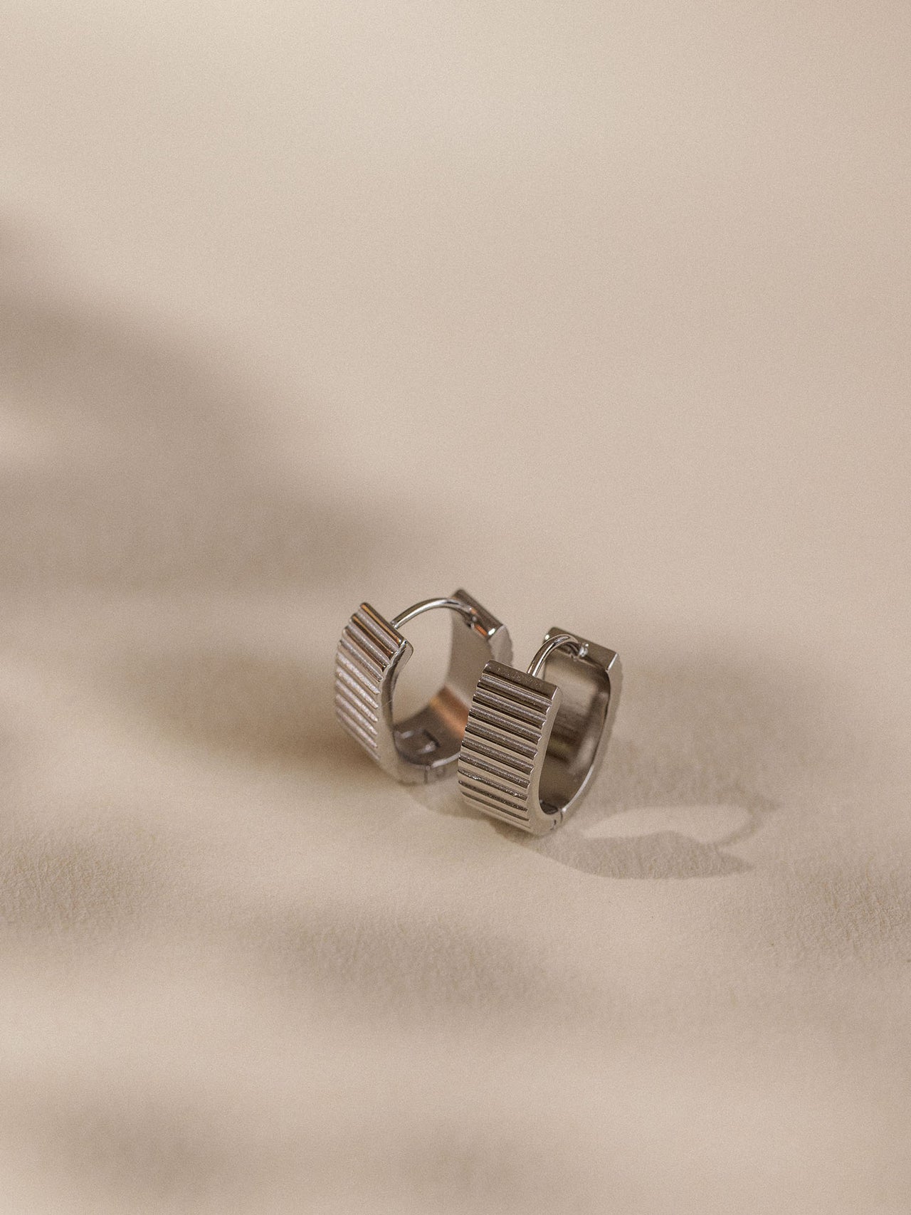 Nickelfreie, goldene Creolen mit strukturiertem Design von PURELEI auf sanftem Untergrund.