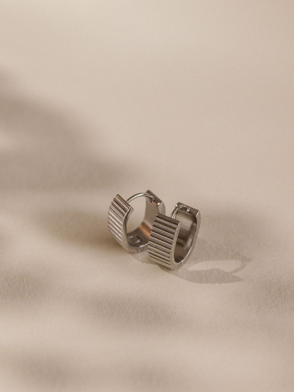 Nickelfreie, goldene Creolen mit strukturiertem Design von PURELEI auf sanftem Untergrund.