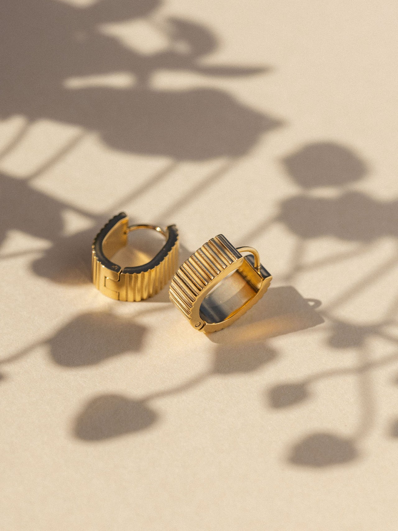 Goldene Ringe mit strukturiertem Design auf sanftem Hintergrund, PURELEI inspiriert.