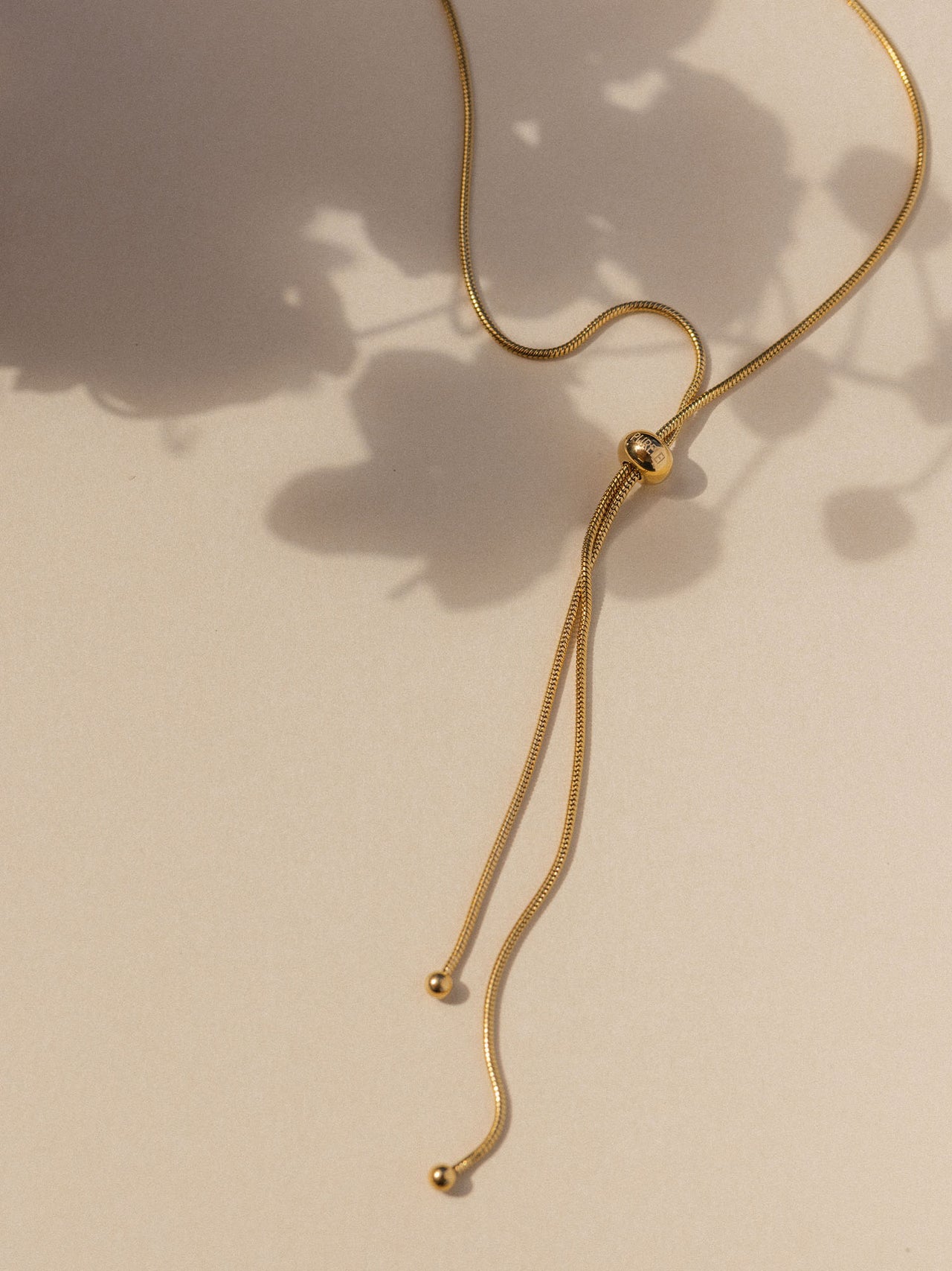 Elegante, goldene Kette mit minimalistischen Details von PURELEI, sanfte Lichtstimmung.