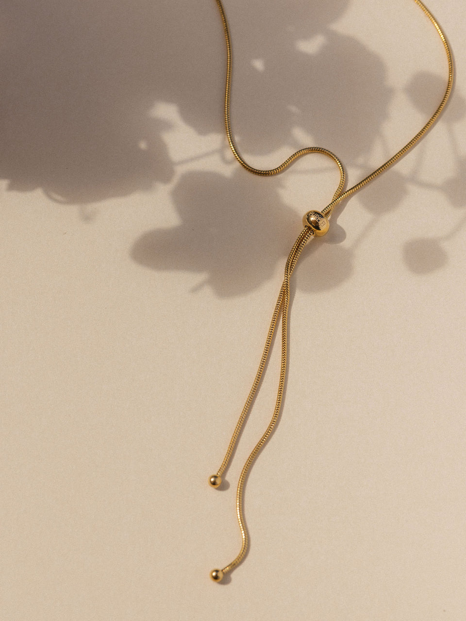 Elegante, goldene Kette mit minimalistischen Details von PURELEI, sanfte Lichtstimmung.