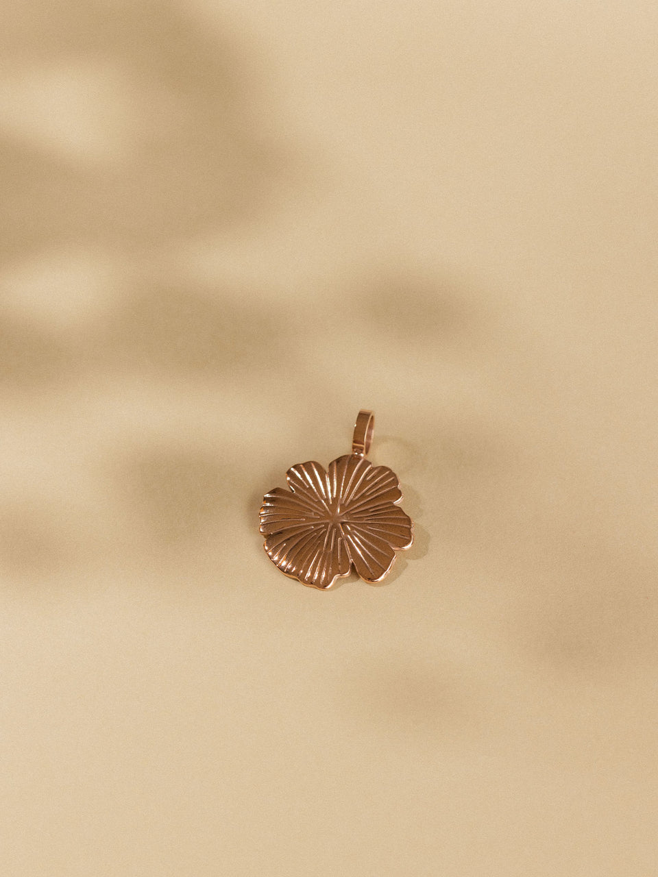 Bronzener Hibiskus-Anhänger auf sanftem Hintergrund, PURELEI inspiriert.