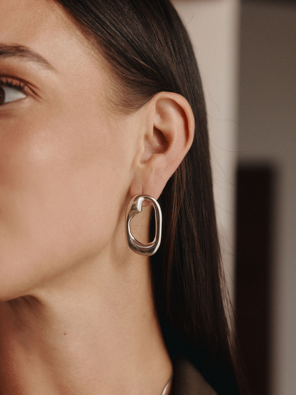Silberne Ohrringe mit organischer Form, getragen von einer Frau, PURELEI.