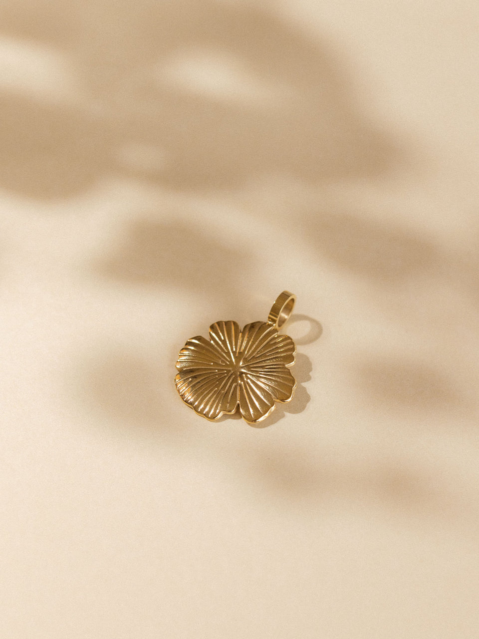 Goldener Hibiskus-Anhänger von PURELEI auf sanftem Hintergrund, elegant und tropisch inspiriert.