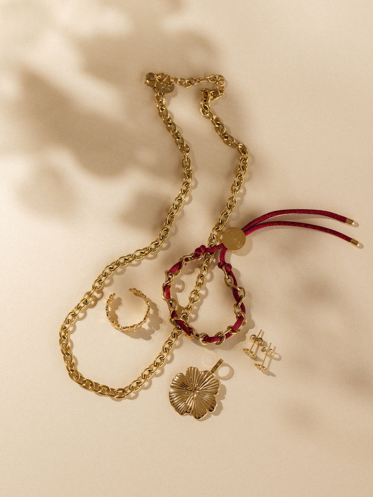 Goldene Kette und Armband mit floralen Details, PURELEI Schmuck auf sanftem Hintergrund.