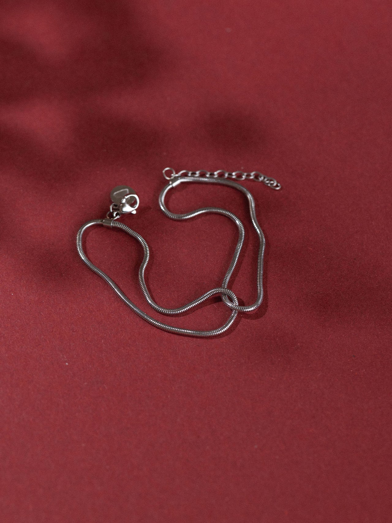 Zarte, roségoldene Kette mit elegantem Design auf rotem Hintergrund – PURELEI.