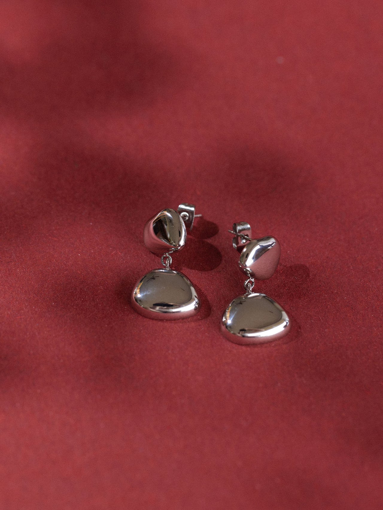 Silberne Ohrringe mit organischem Design auf rotem Hintergrund von PURELEI.