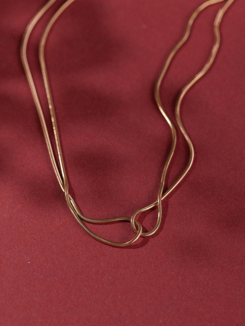 Zweifädige, roségoldene Kette auf rotem Hintergrund, elegant und modern – PURELEI.