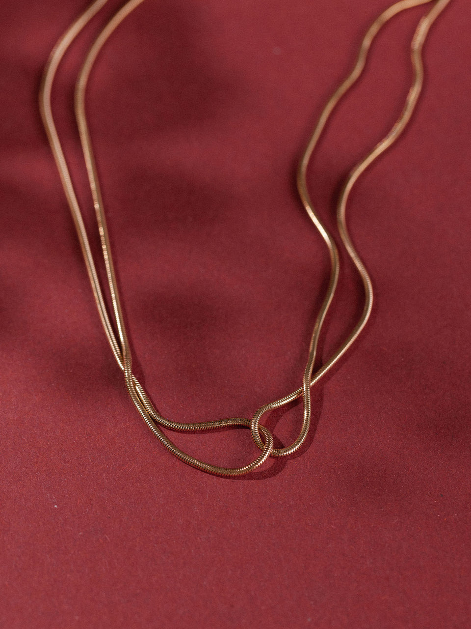 Zweifädige, roségoldene Kette auf rotem Hintergrund, elegant und modern – PURELEI.