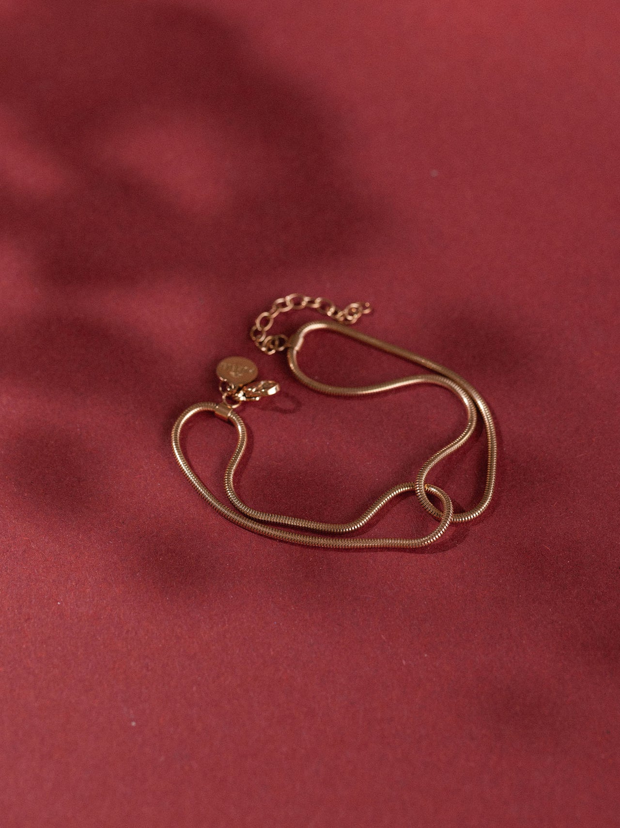 Roségoldene Kette mit zarten Anhängern auf rotem Hintergrund von PURELEI.