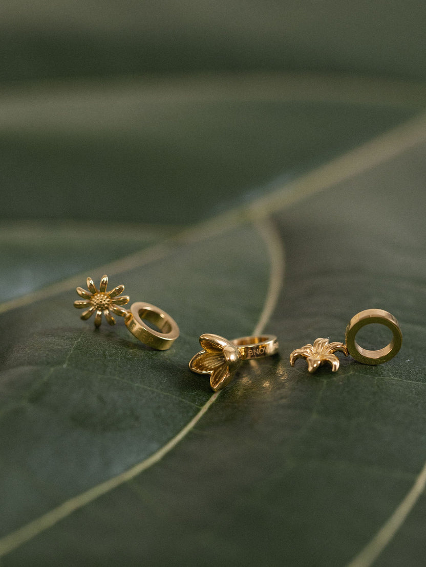 Narzisse Geburtsblume Dezember Charm von PURELEI, 18K vergoldet, filigranes Blumendesign auf grünem Blatt, elegant und feminin.