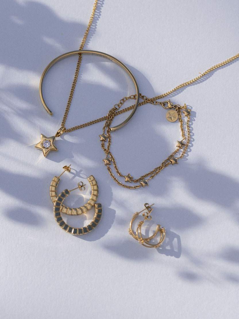 Goldene Schmuckstücke von PURELEI: Kette mit Stern, Armband, Creolen und Ohrstecker, elegant und feminin.