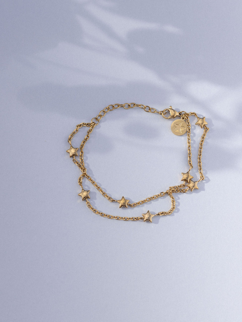 Goldene Kette mit Sternenanhängern auf sanftem Hintergrund von PURELEI.