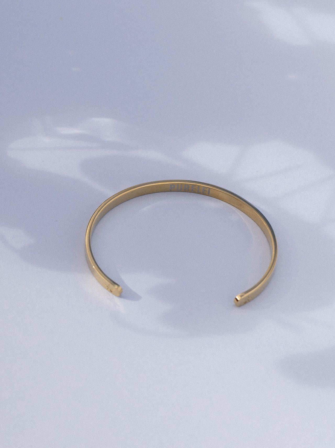 Elegantes, goldenes Armband von PURELEI auf sanftem Hintergrund, minimalistisch und modern.