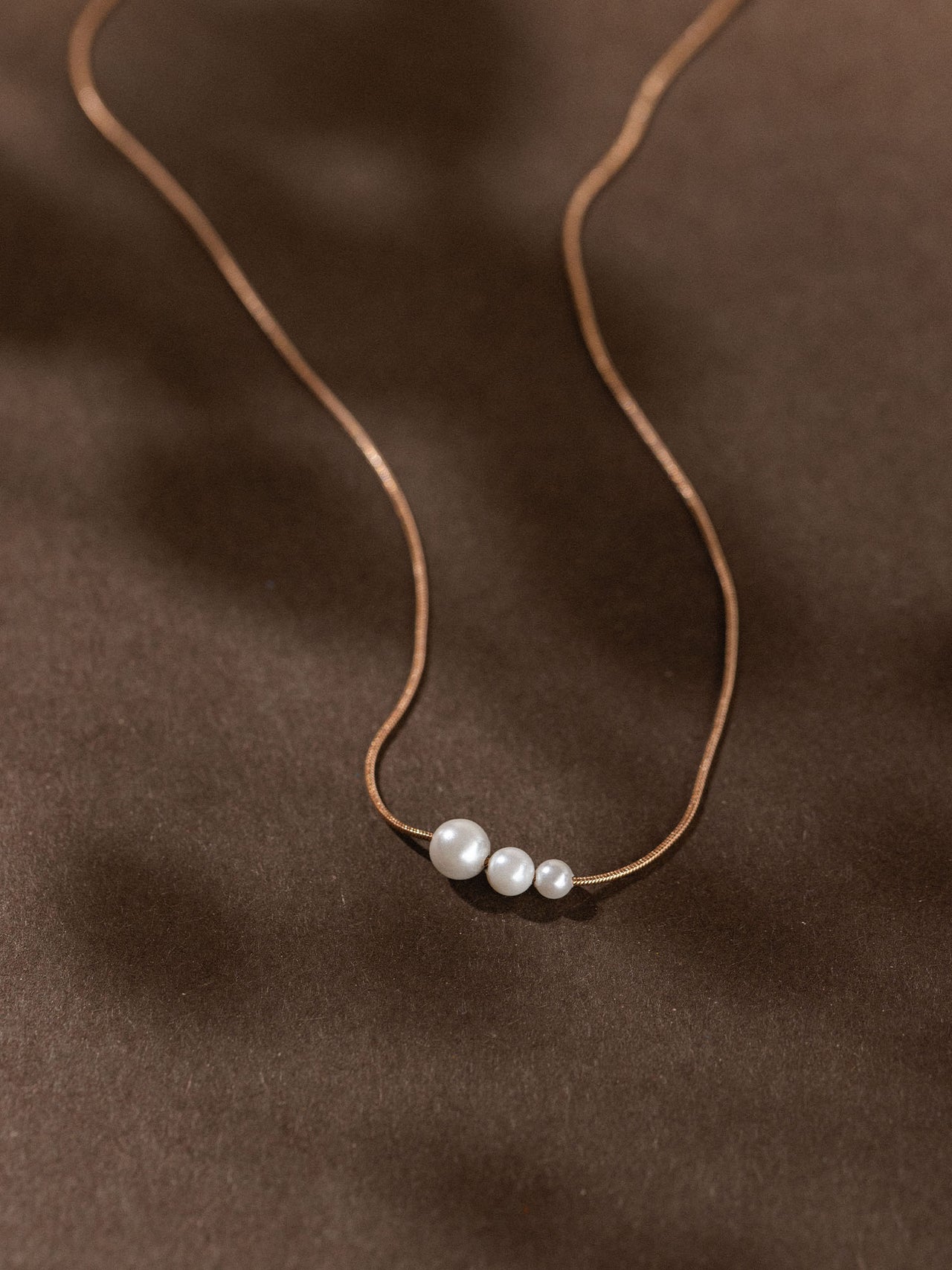 Zarte PURELEI Kette mit drei runden Anhängern in warmem Braunton, elegant und minimalistisch.