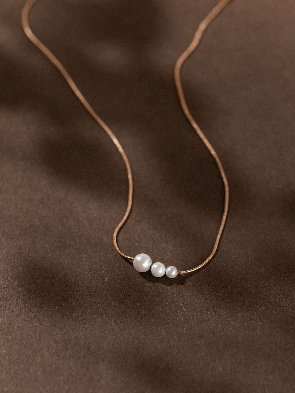 Zarte PURELEI Kette mit drei runden Anhängern in warmem Braunton, elegant und minimalistisch.